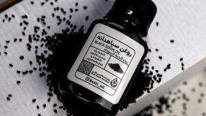 یک بسته روغن سیاه دانه در کنار دانه های سیاه دانه