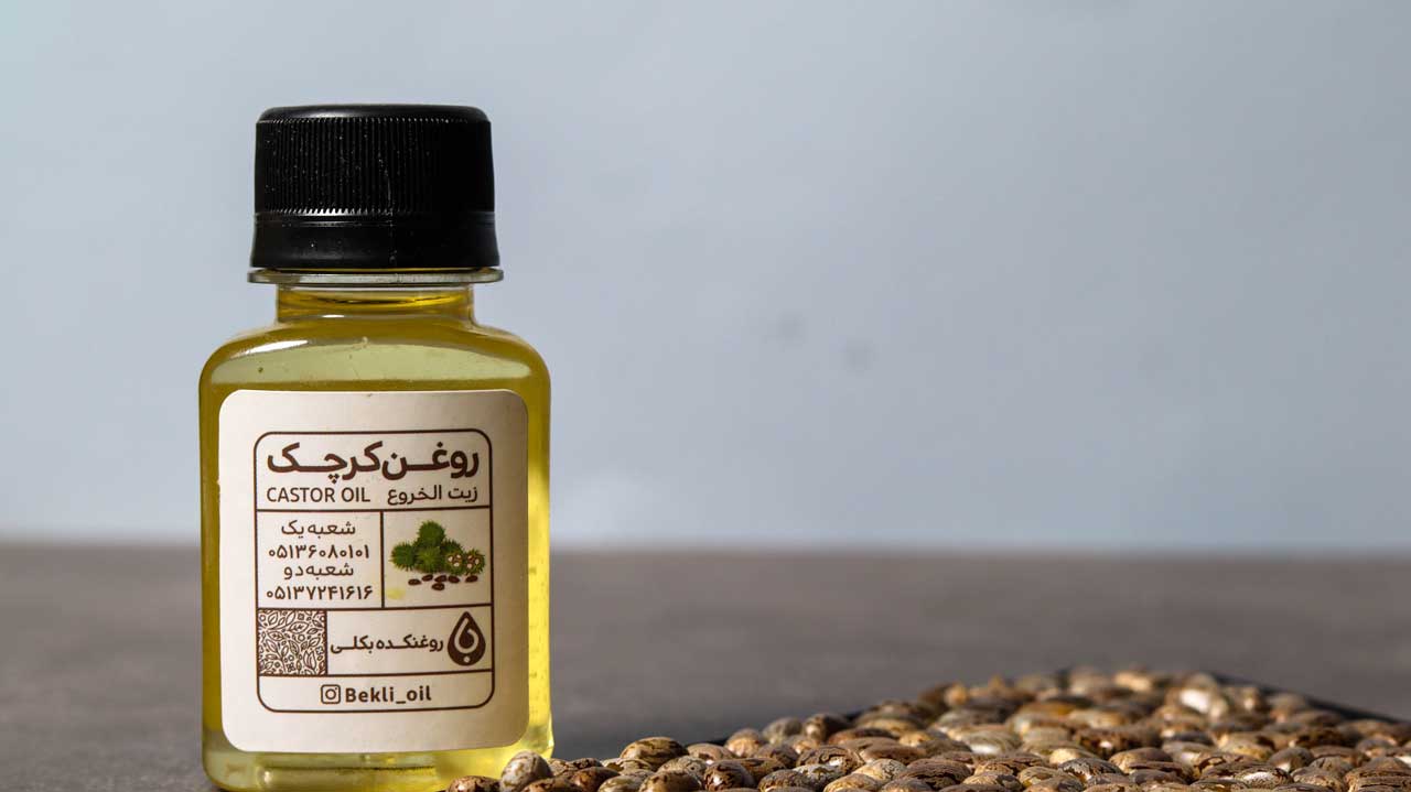 یک عدد روغن کرچک در کنار دانه های کرچک