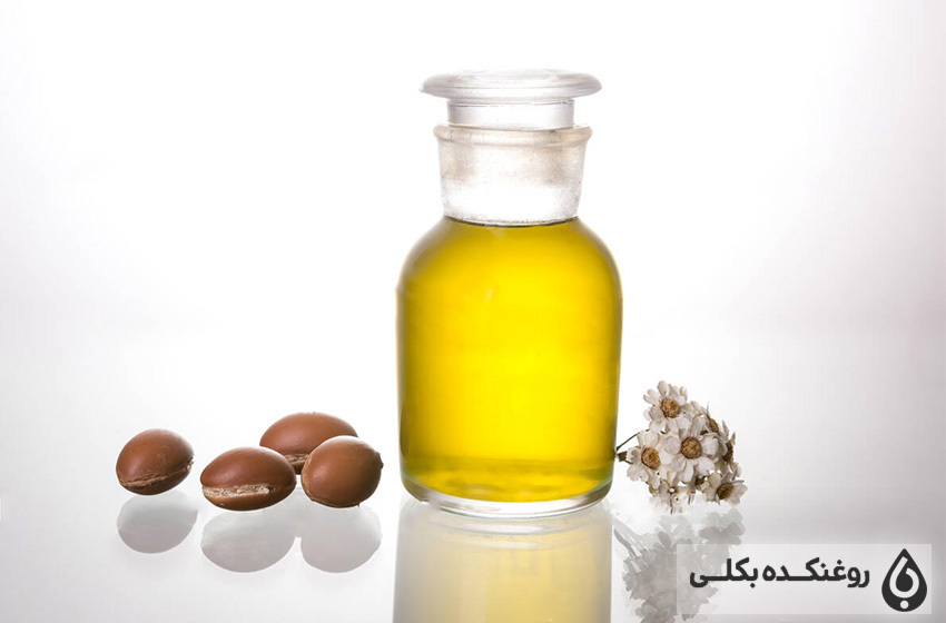 یک شیشه حاوی روغن آرگان و چند دانه آرگان