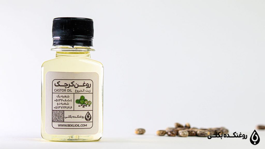 یک شیشه حاوی روغن کرچک به همراه دانه های کرچک بر روی زمین
