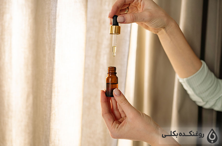 دستی در حال گرفتن شیشه روغن آرگان
