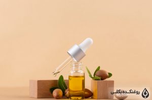 یک شیشه حاوی روغن آرگان و قطره چکان و دانه های آرگان