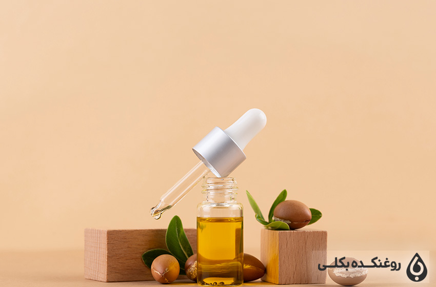 یک شیشه حاوی روغن آرگان و قطره چکان و دانه های آرگان