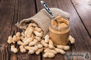 یک شیشه حاوی کره بادام زمینی و دانه های بادام زمینی