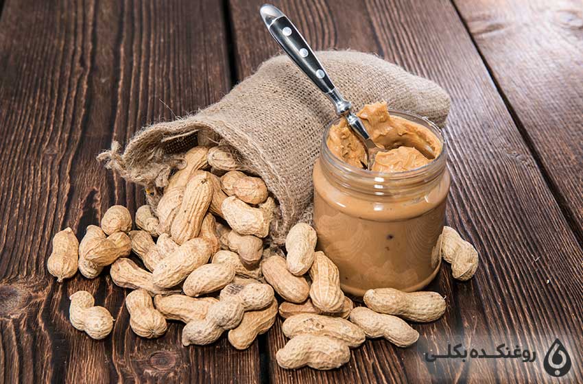 یک شیشه حاوی کره بادام زمینی و دانه های بادام زمینی