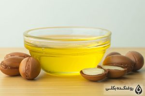 یک ظرف حاوی روغن آرگان به همراه دانه های آرگان