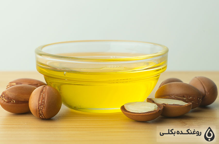یک ظرف حاوی روغن آرگان به همراه دانه های آرگان