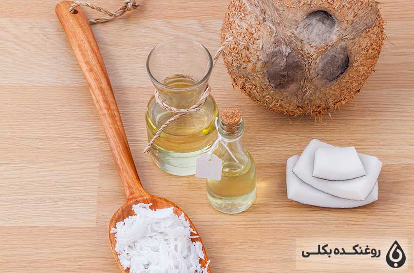 دو شیشه حاوی روغن نارگیل به همراه یک نارگیل و یک قاشق دارای تکه های نارگیل
