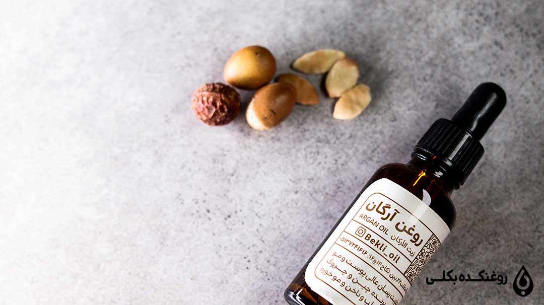 شیشه روغن آرگان در کنار تعدادی دانه آرگان
