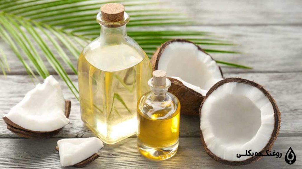 دو بطری روغن نارگیل در کنار دو تکه نارگیل تازه