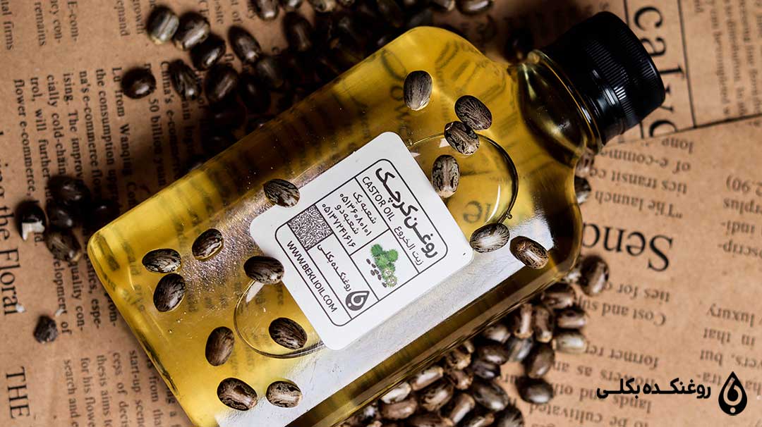ظرف روغن کرچک با تعدادی دانه کرچک روی آن