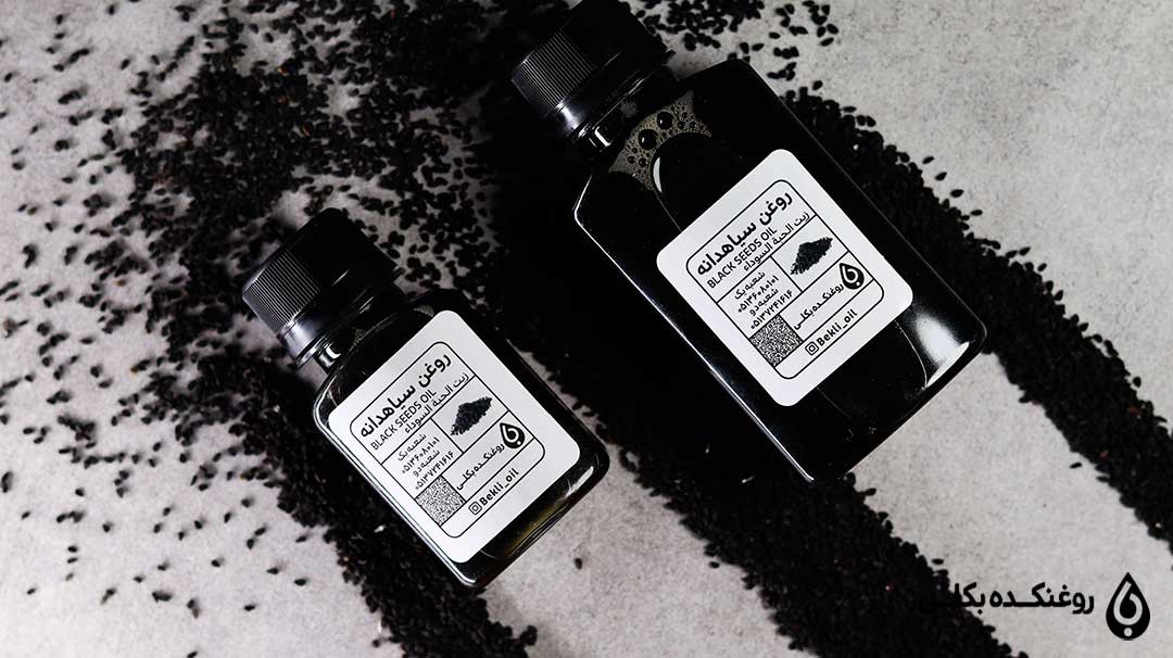 دو قوطی روغن سیاه دانه که اطراف آن مقداری سیاه دانه ریخته است