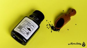روغن سیاه دانه در کنار مقداری سیاه دانه در قاشق