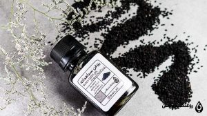 مقداری سیاهدانه ریخته شده در کنار ظرف روغن سیاه دانه