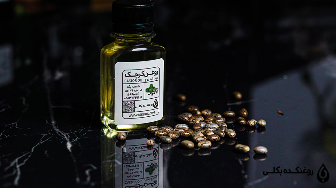 یک شیشه روغن کرچک در کنار دانه های کرچک