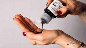 روغن سیاه دانه در حال ریخته شدن از قوطی روی دست