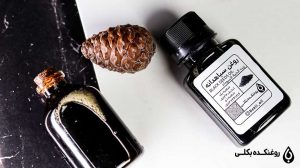 دو ظرف روغن سیاه دانه در کنار میوه درخت کاج