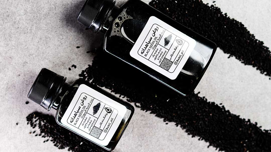 دو قوطی روغن سیاه دانه در کنار پودر سیاه دانه