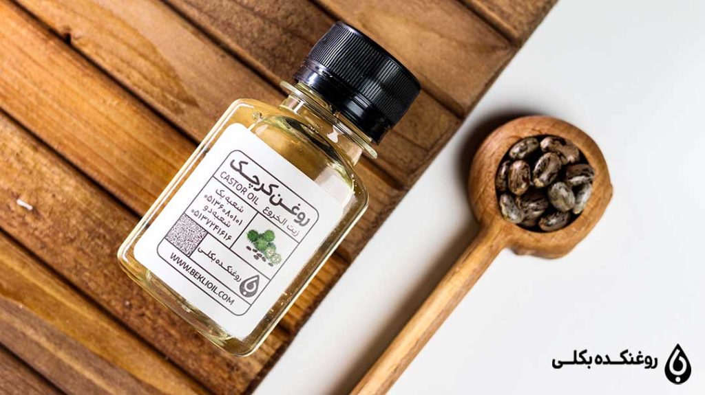 روغن کرچک طبیعی در کنار دانه های کرچک داخل قاشق