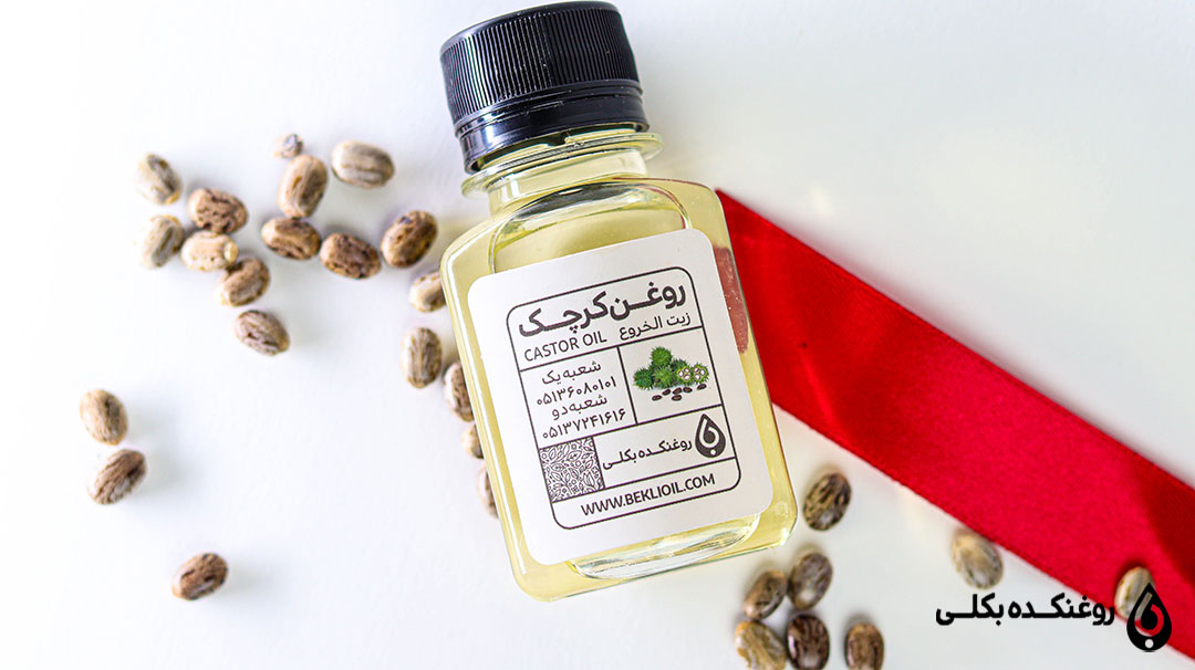 ظرف درب دار روغن کرچک در کنار دانه های کرچک