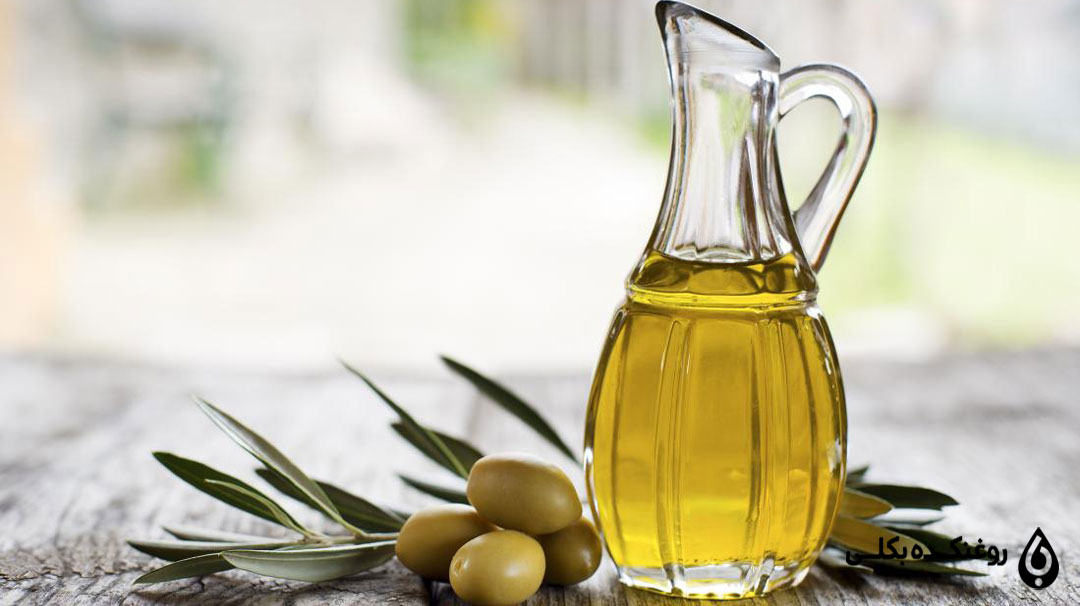 روغن زیتون در پارچ بلوری در کنار زیتون تازه