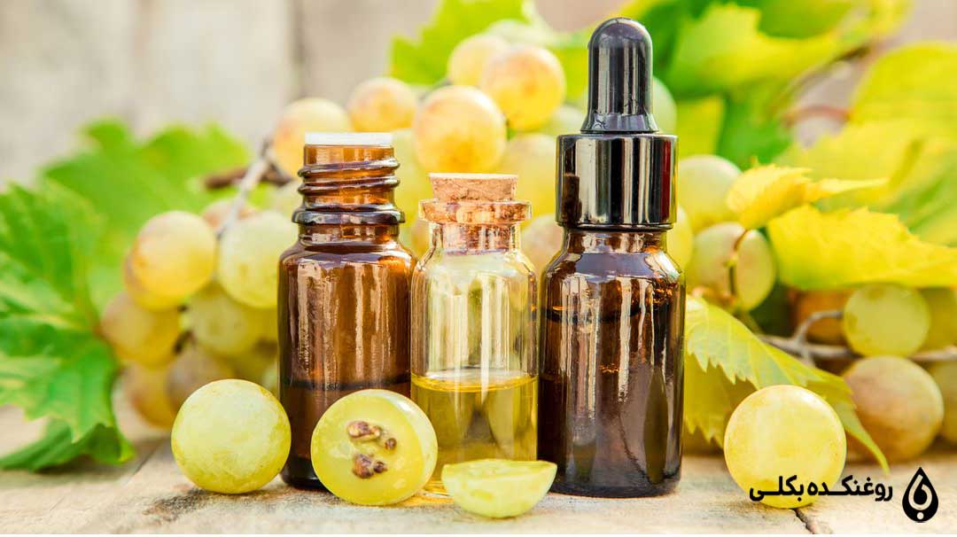 روغن هسته انگور در ظرف شیشه ای در کنار انگور تازه